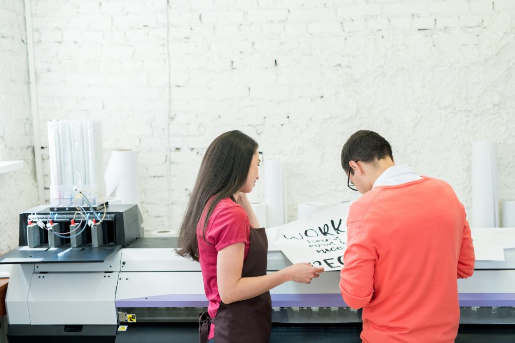 Printing specialists examining banner in office
